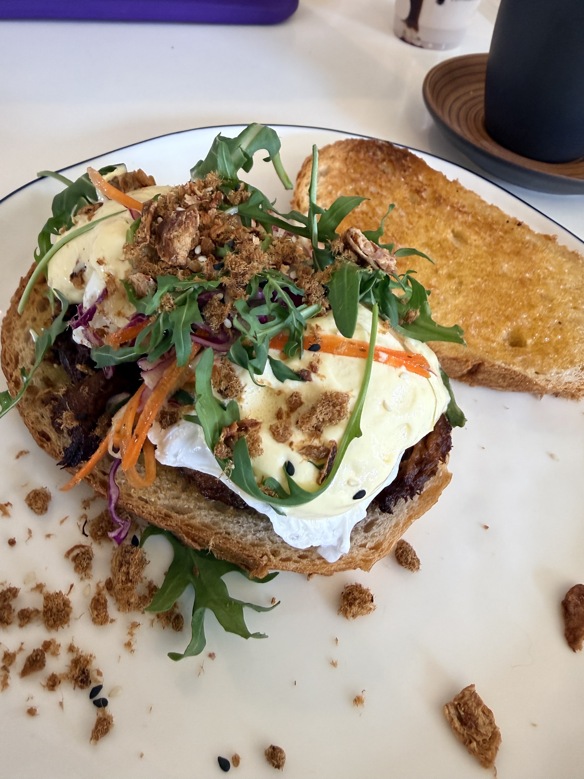 Poached eggs with hollandaise, rocket and a crumb topping on toast