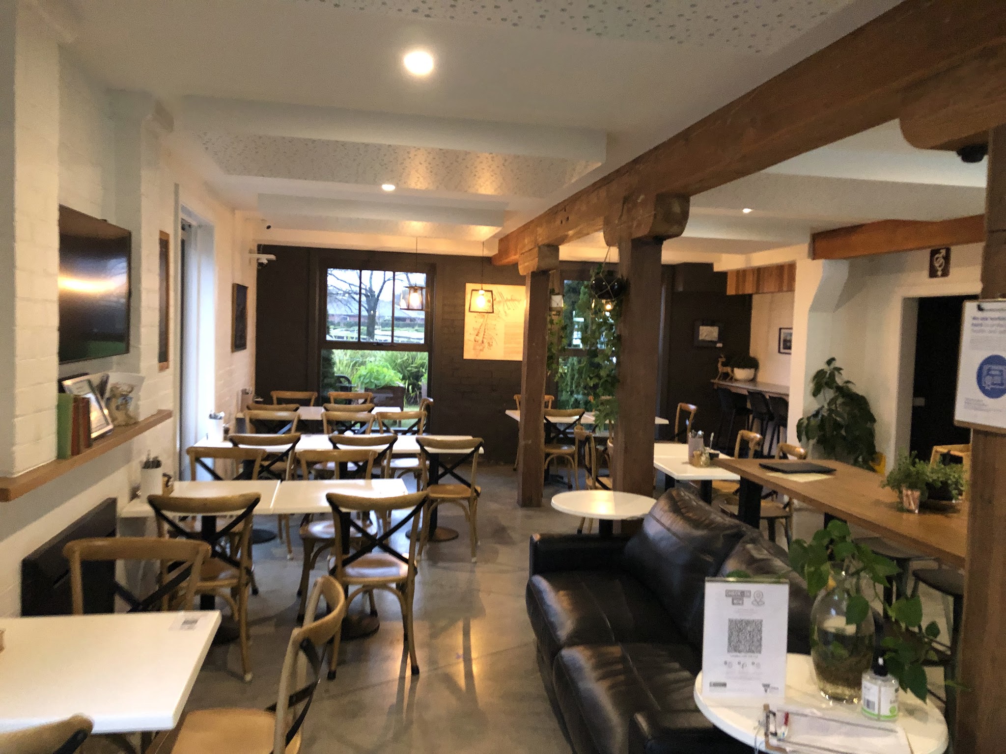 The dining room with timber beams, bentwood chairs, a leather couch and big windows